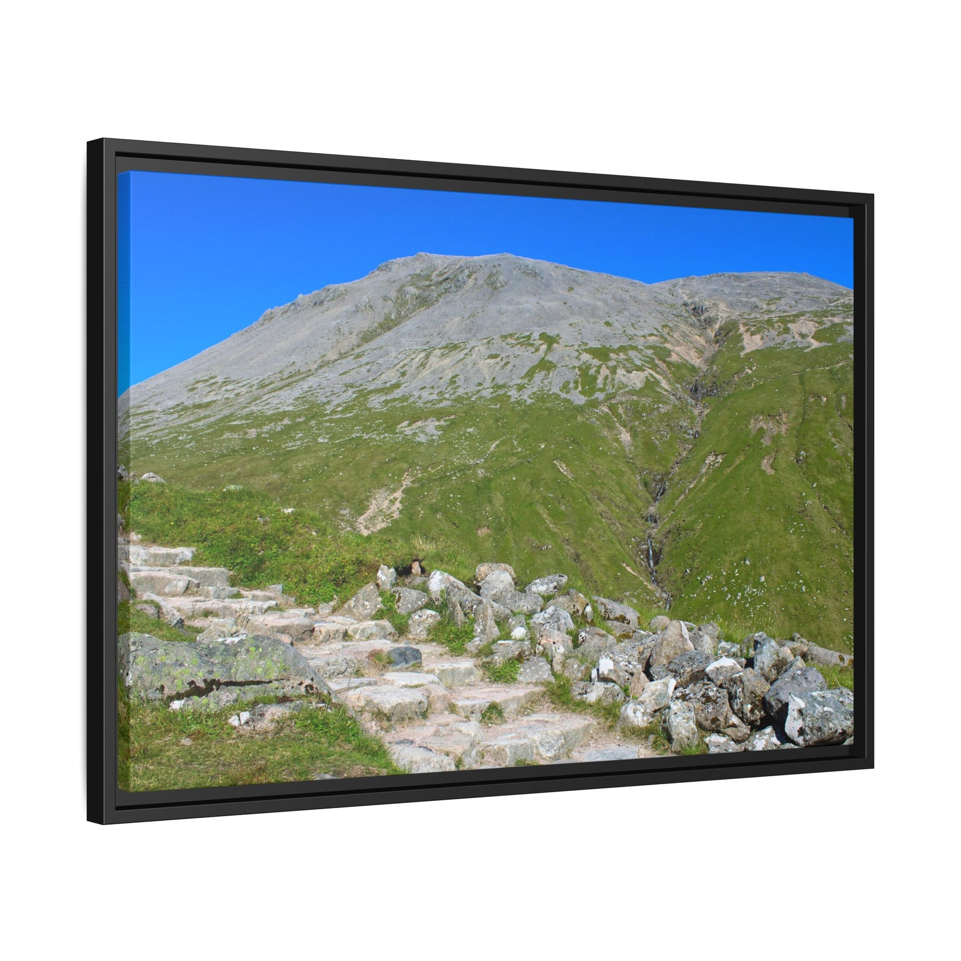 Framed picture of a mountain landscape with greenery and clear blue sky.
