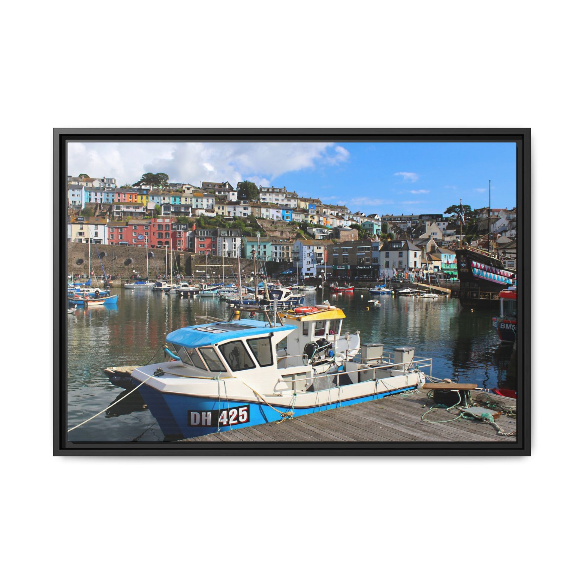 Framed photograph of a harbour scene with a boat and colourful houses.