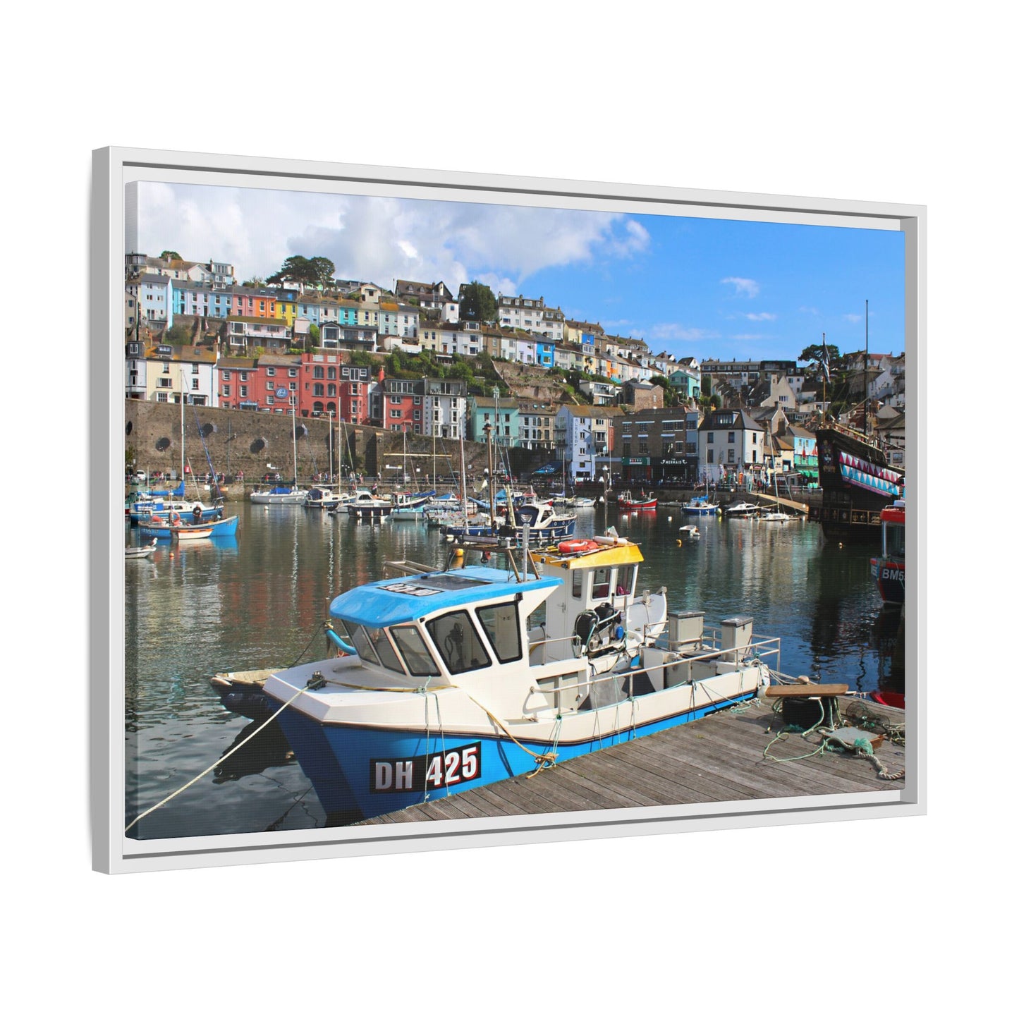 Framed picture of a harbour scene with boats and colourful buildings.