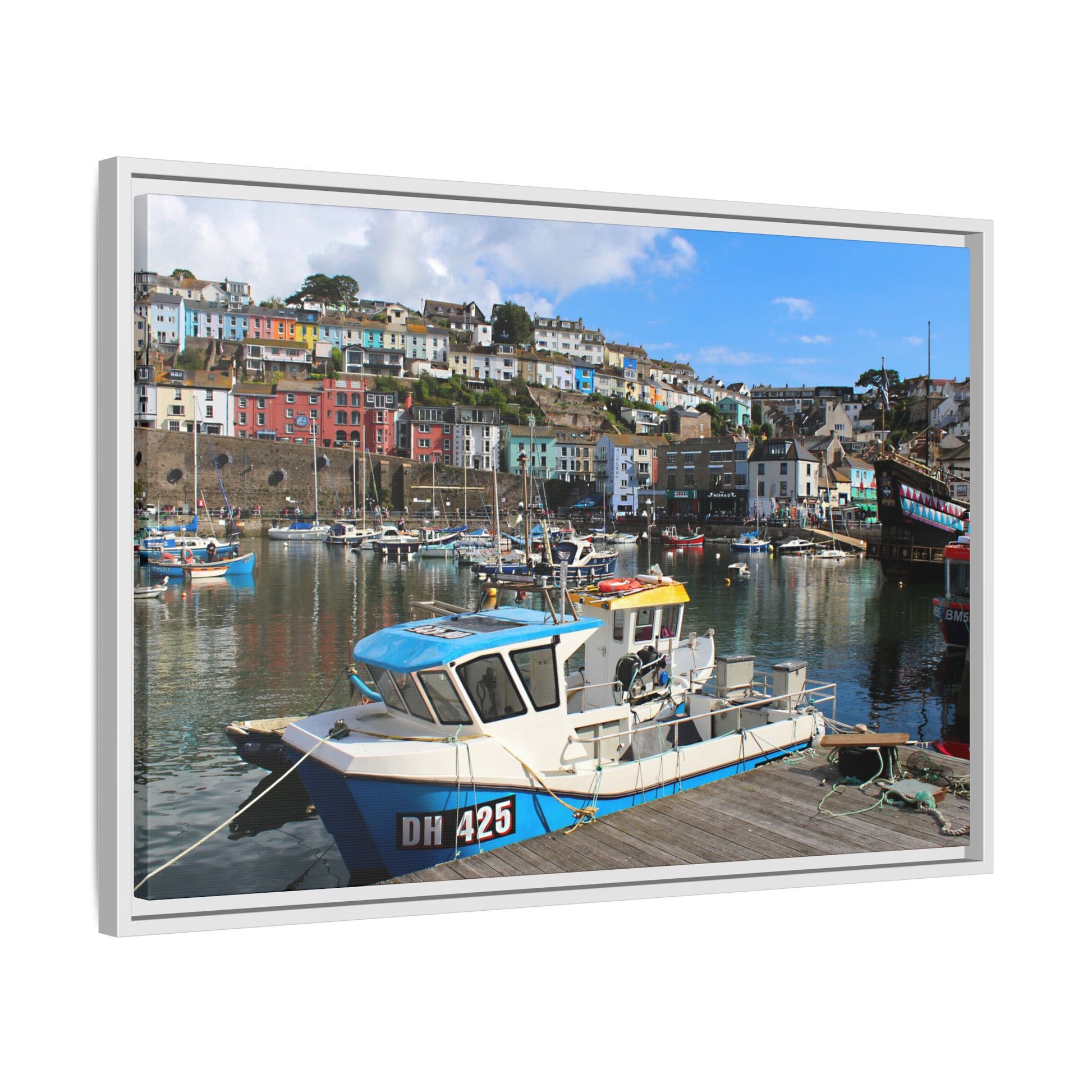 Framed picture of a harbour scene with boats and colourful buildings.