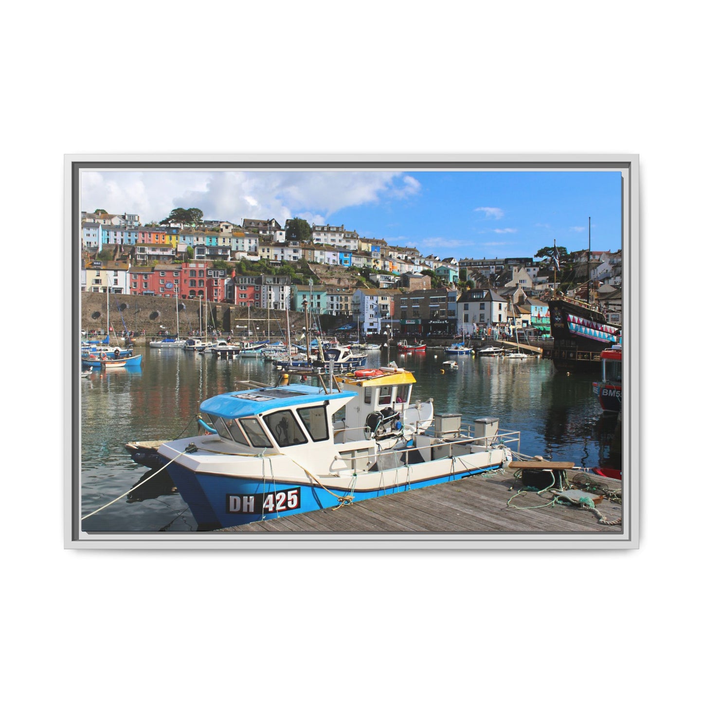 Boat docked at a harbour with colourful houses in the background