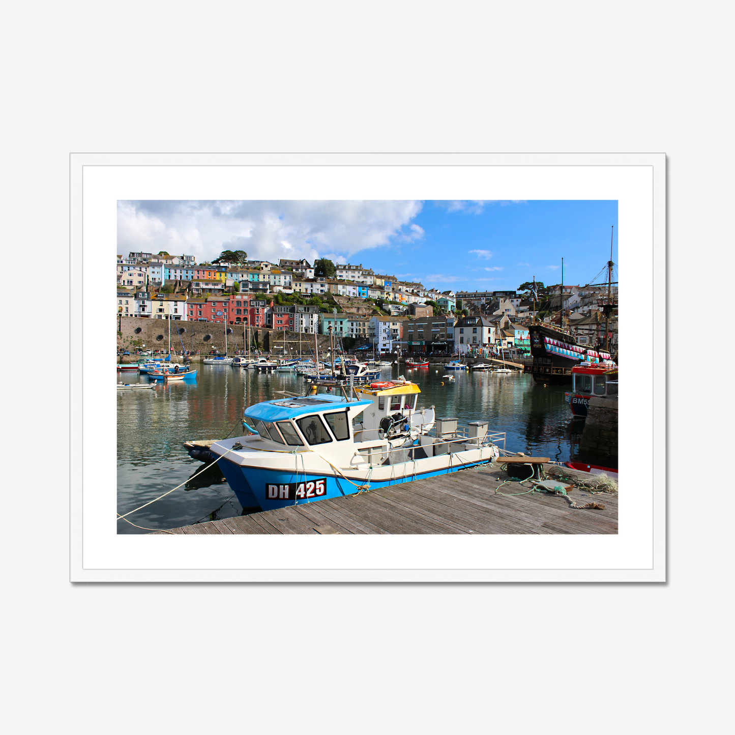 Framed photograph of a harbour scene with boats and colourful buildings.