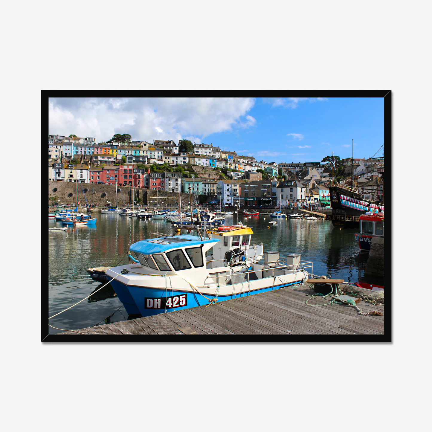 Framed photograph of a harbour scene with boats and colourful buildings.