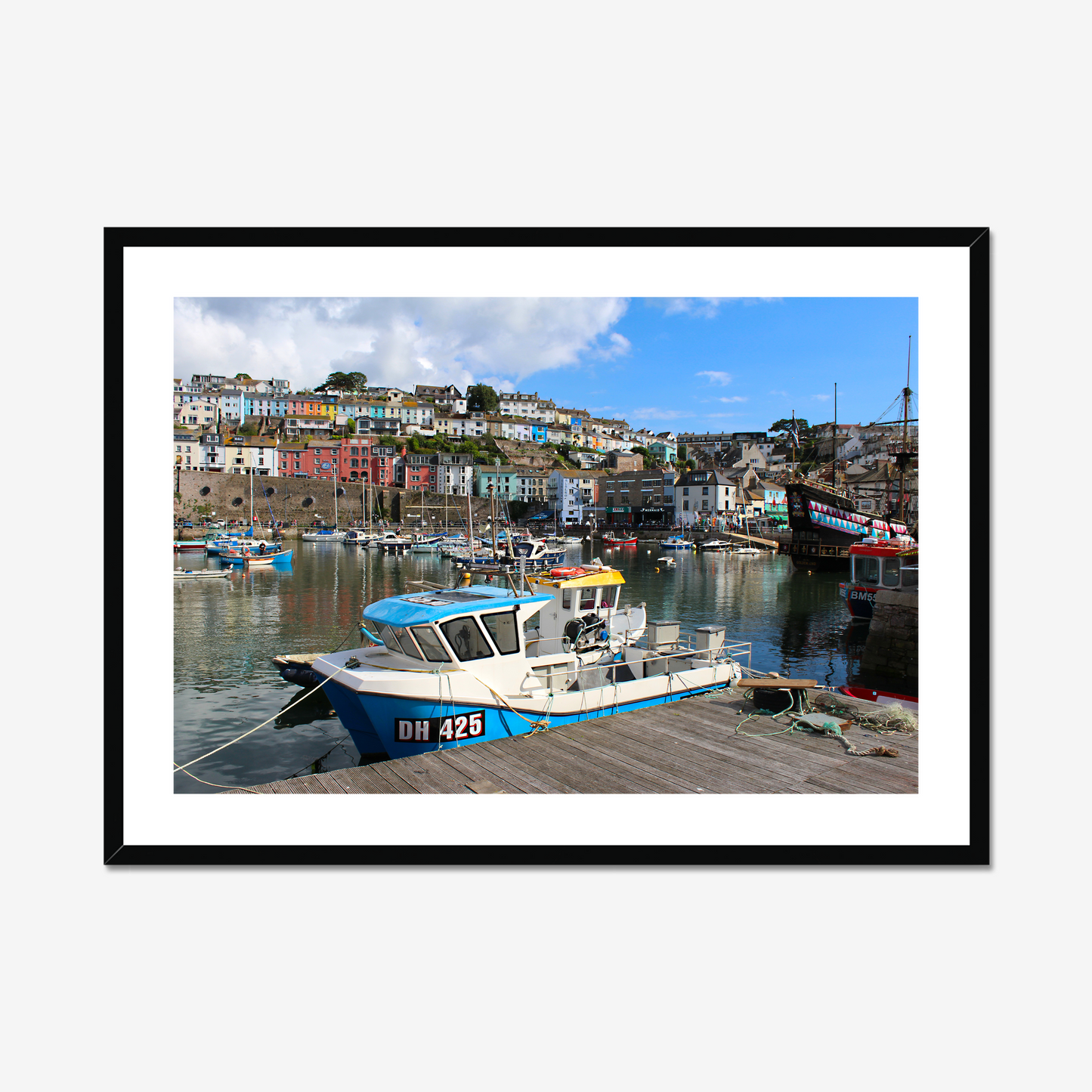 Framed photograph of a harbour scene with boats and colourful buildings.
