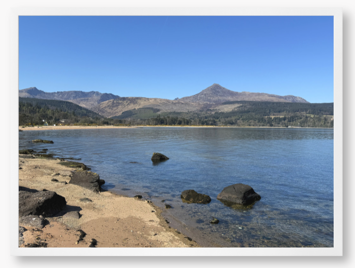A framed photo of Brodick Bay on the Isle of Arran, showing the beach and mountains in the background with a clear blue sky.