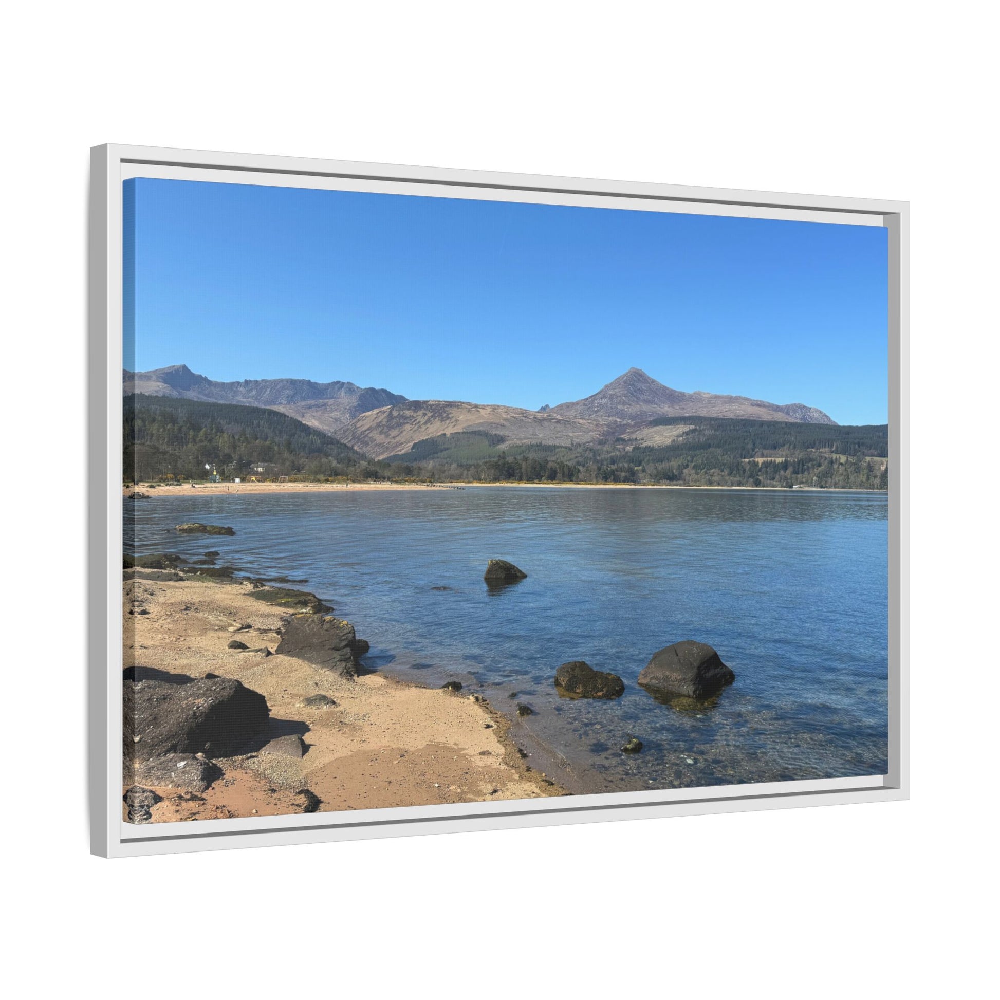 Framed picture of a mountainous landscape with a lake and rocky shore.