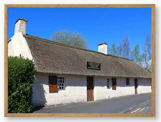 Framed Photo Of A Traditional thatched cottage with a blue sky and trees in the background