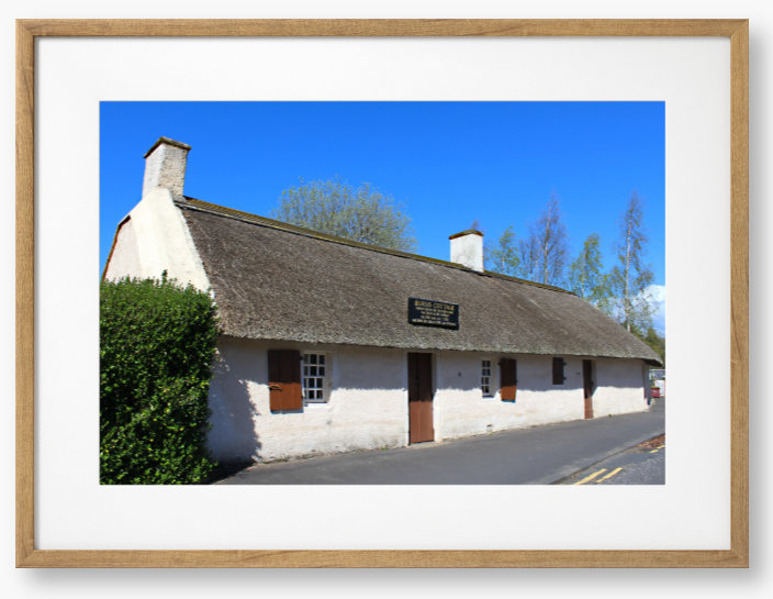 Framed Photo Of A Traditional thatched cottage with a blue sky and trees in the background