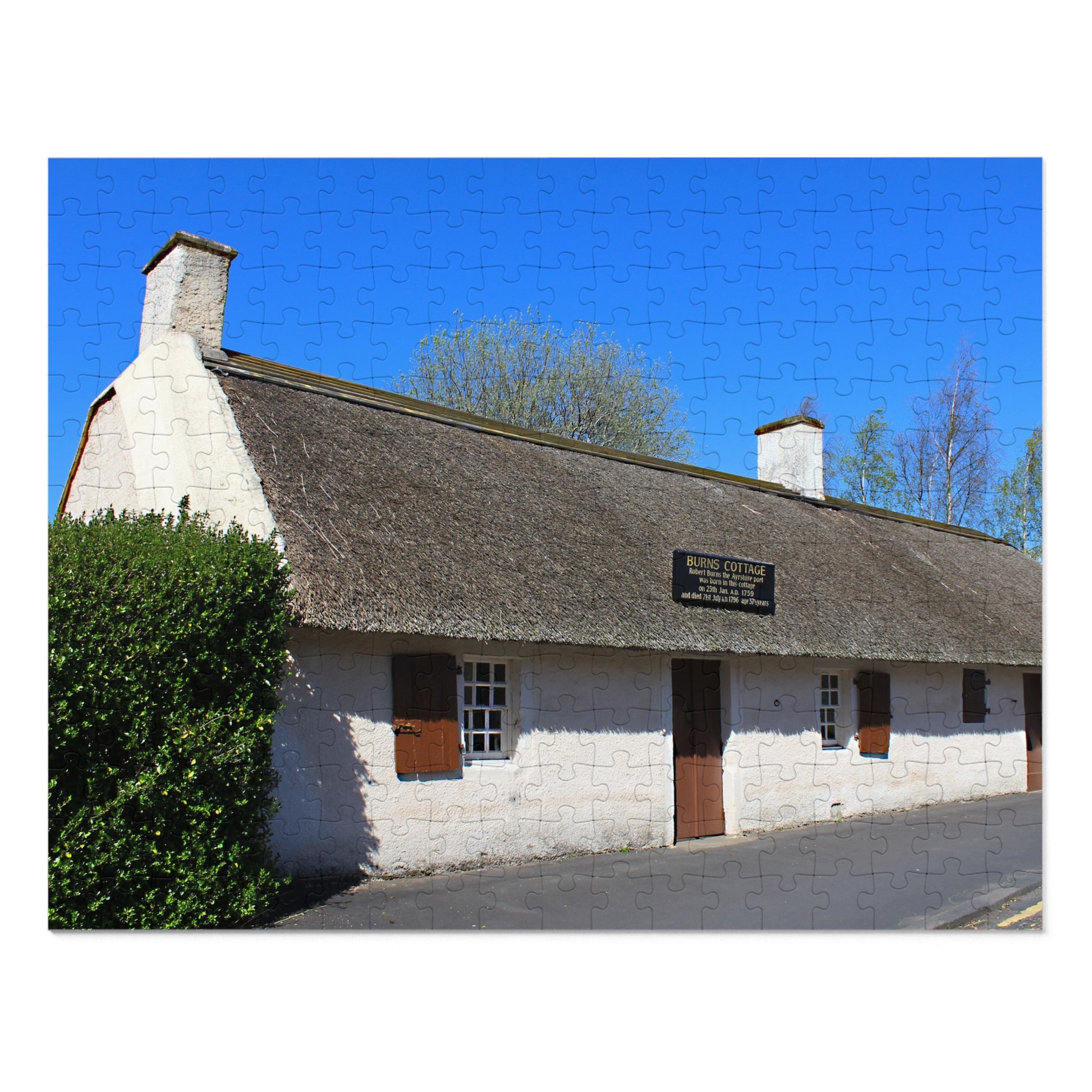 Thatched roof cottage with a sign against a blue sky