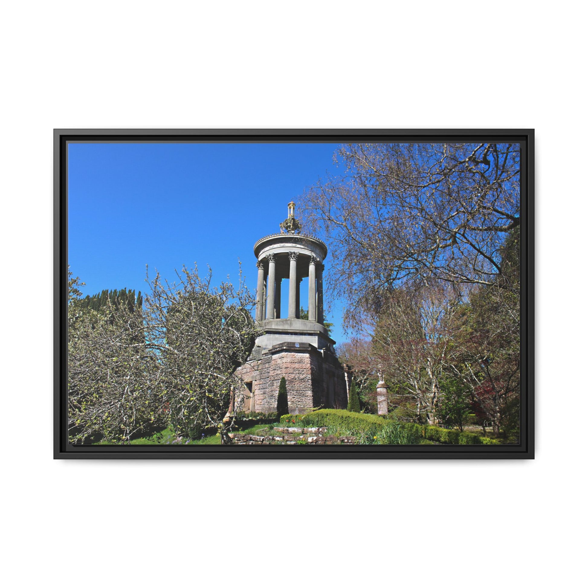 Stone monument with a statue in a park setting, framed by a black border.