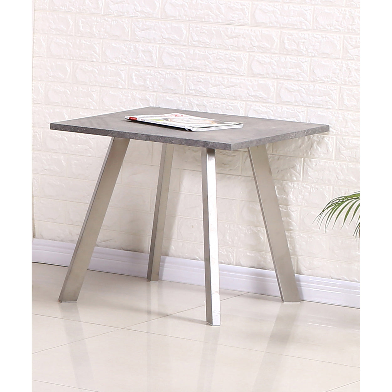Modern lamp table with gray marble top and metal legs against a white brick wall.