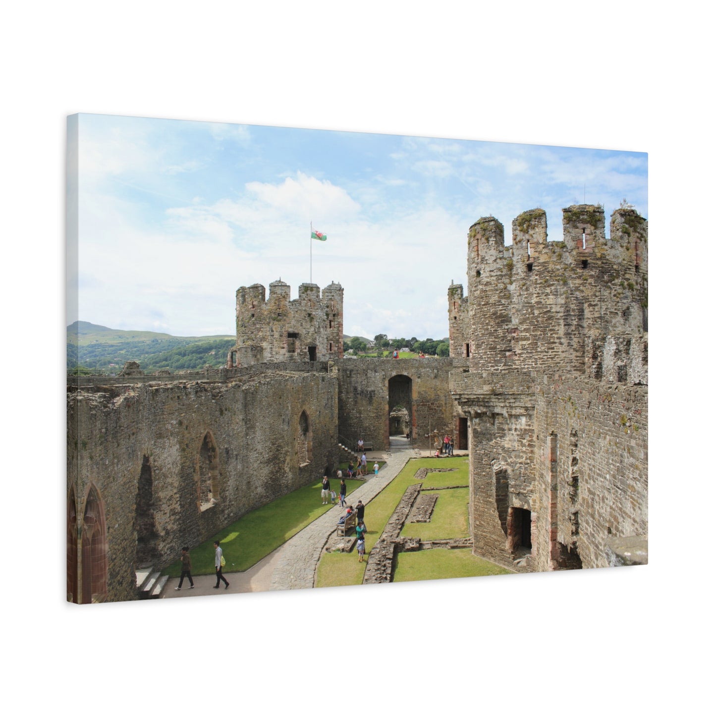 Castle with tourists walking around, surrounded by greenery under a blue sky.