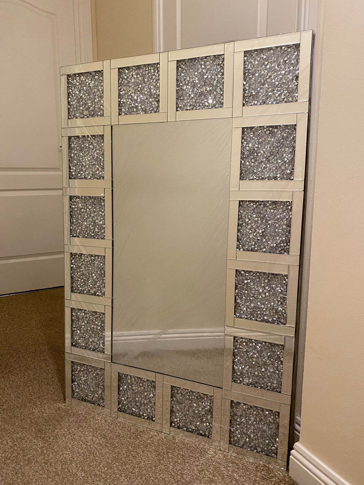A silver square border mirror with crushed crystal embellishments on the border.