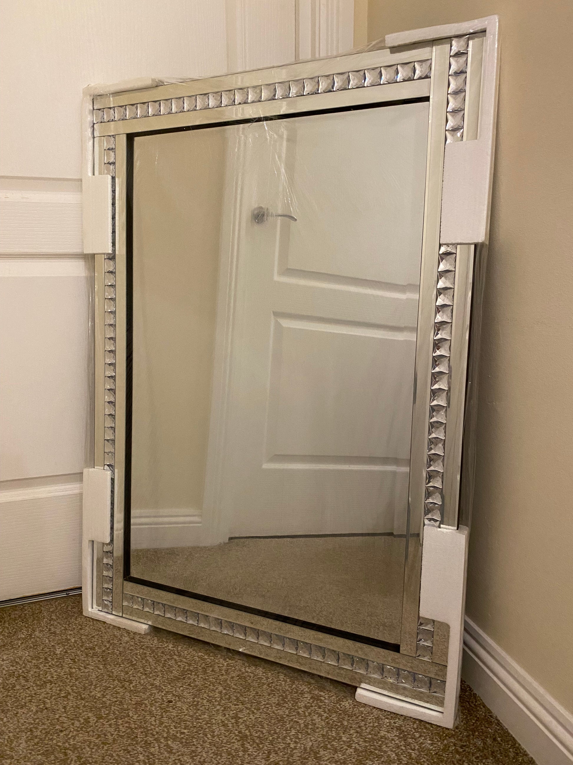 Bevelled edge wall mirror with a diamante frame.