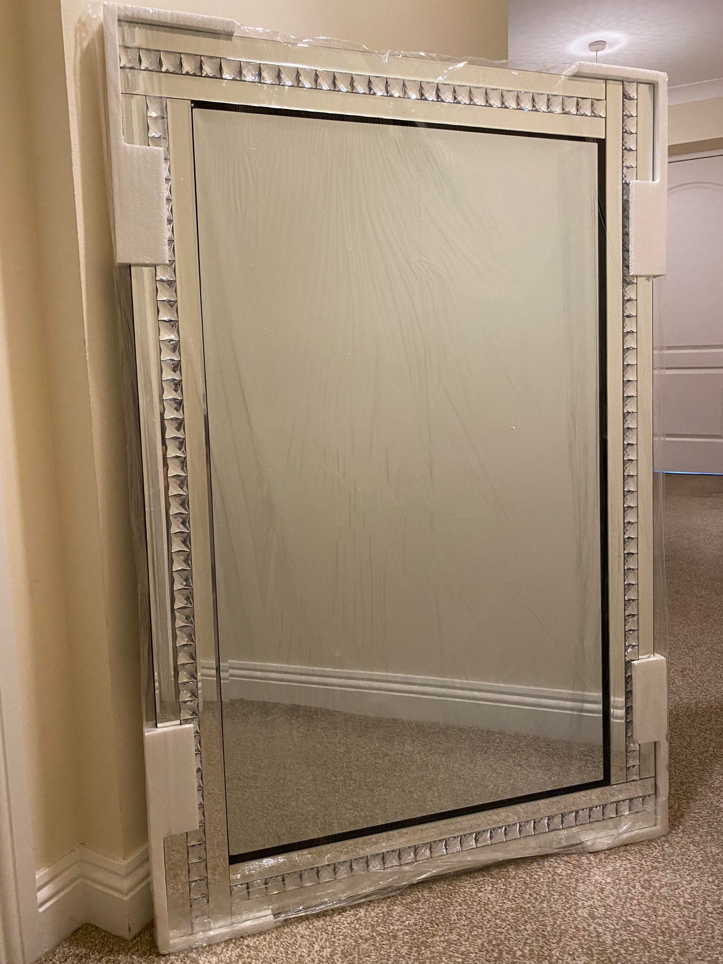 Bevelled edge wall mirror with a diamante frame.