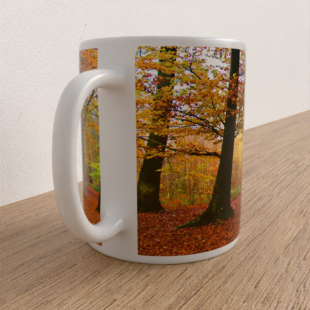 White mug with a scenic design of trees and autumn leaves on a wooden surface.