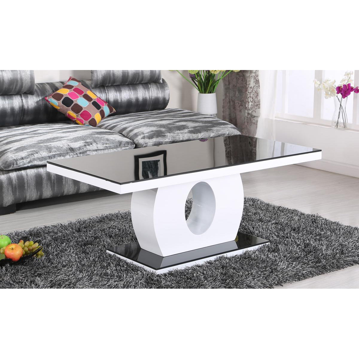 Modern coffee table with a white base and glass top in a living room setting.