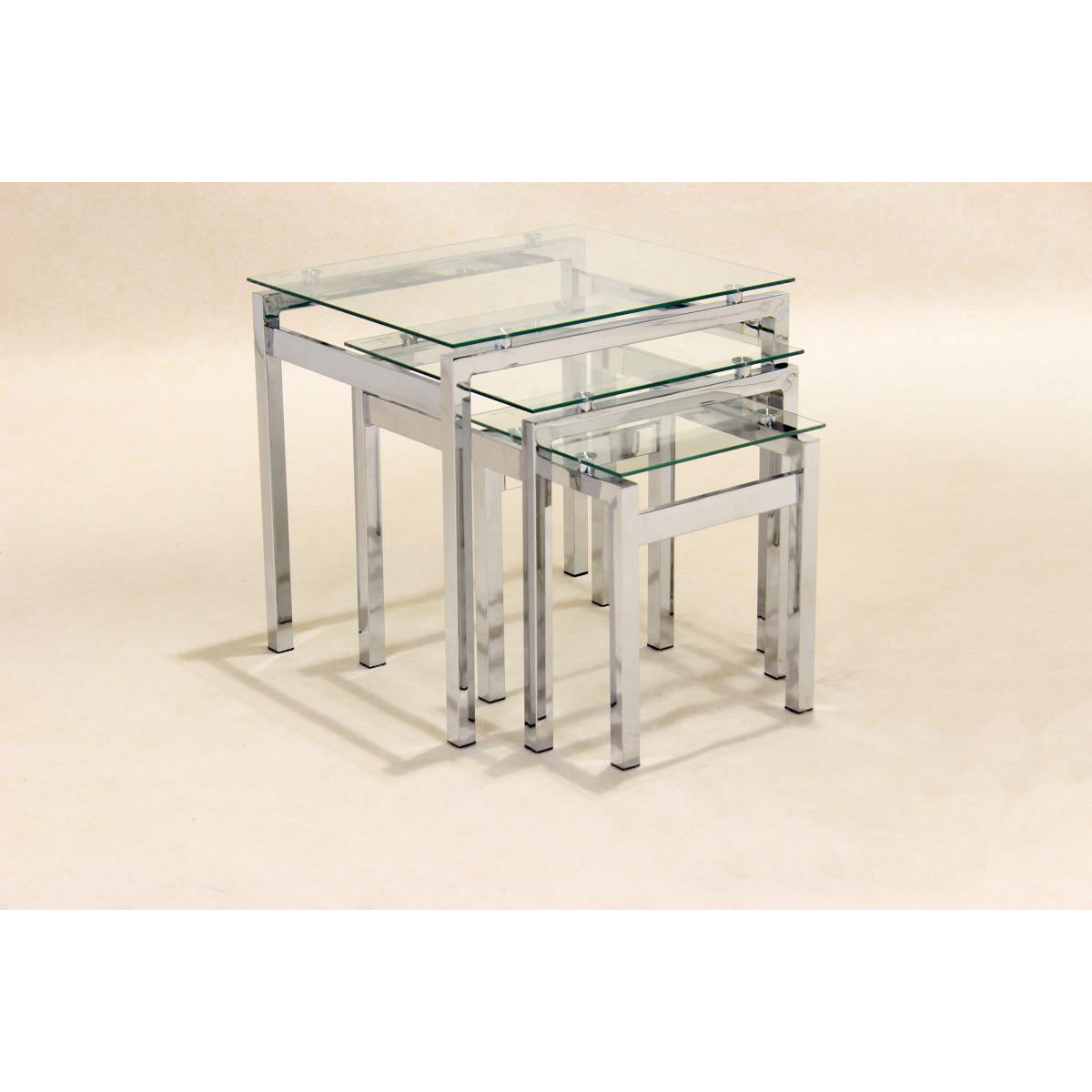 A clear glass nest of three tables with chrome legs, each having a square top and chrome supports.