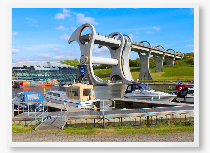 A framed photo of the Falkirk Wheel boat lift with boats docked at a marina under a blue sky.
