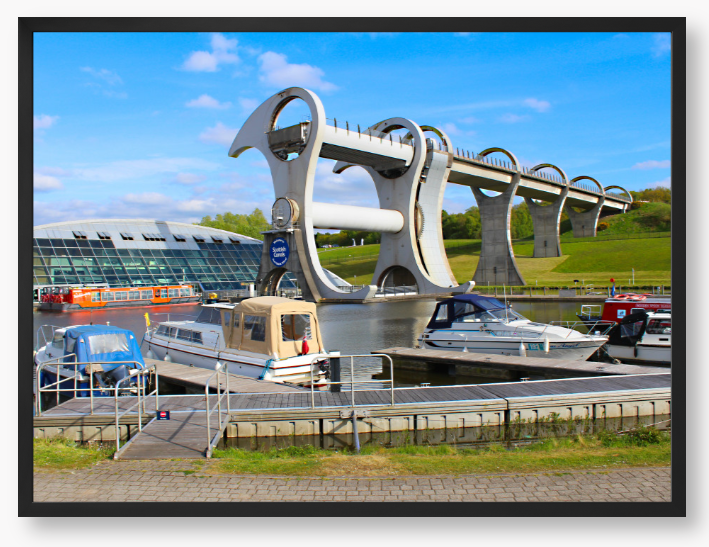 A framed photo of the Falkirk Wheel boat lift with boats docked at a marina under a blue sky.