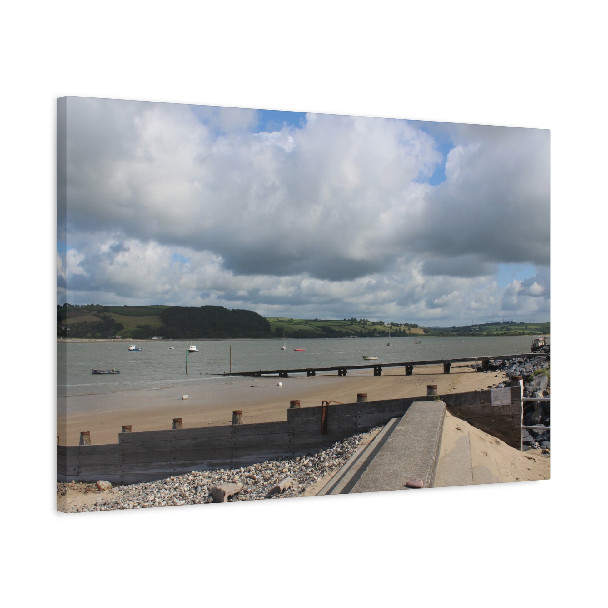 Panoramic view of a coastal scene with a bridge, water, and hills under a cloudy sky.