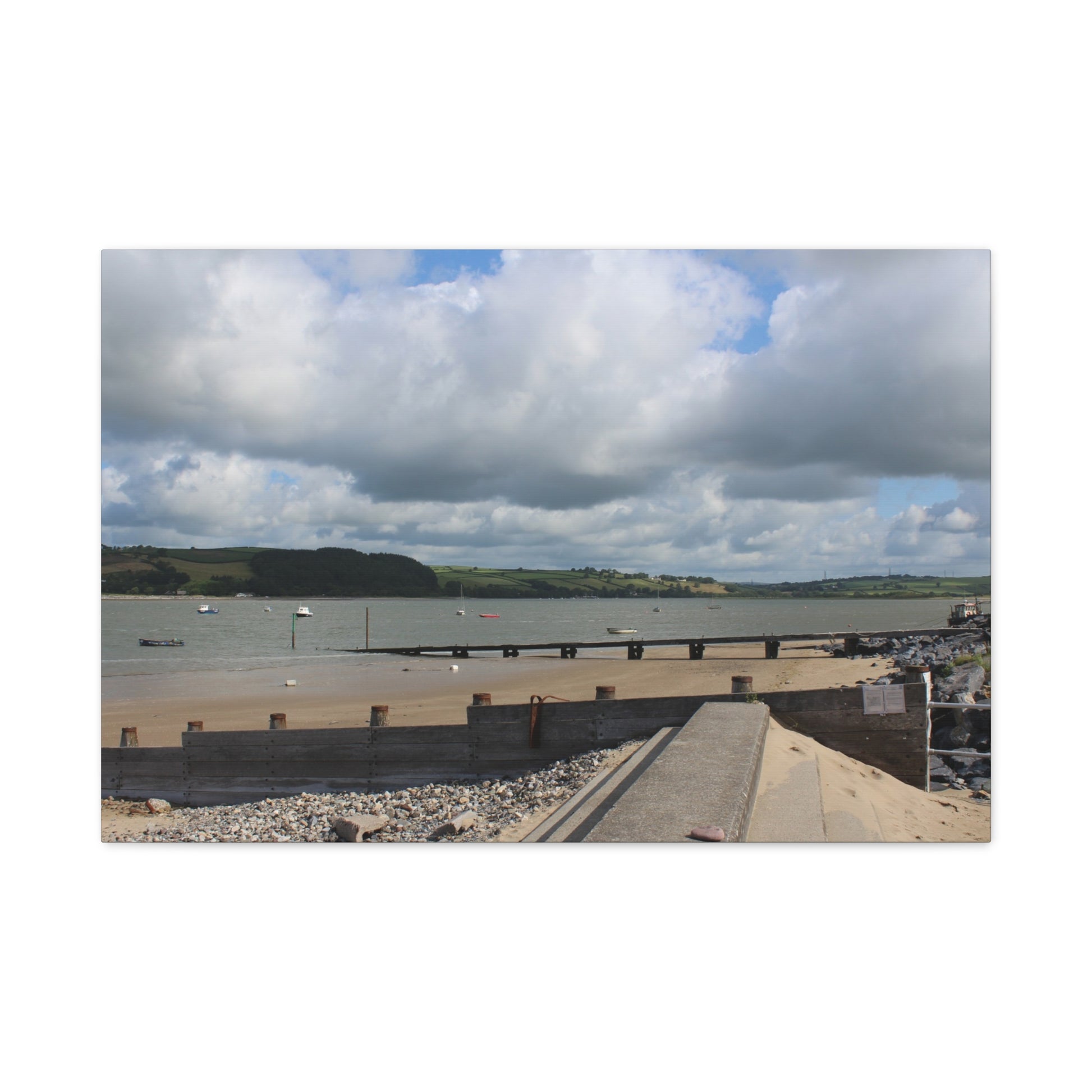 Scenic view of a coastal area with a bridge, water, and cloudy sky.