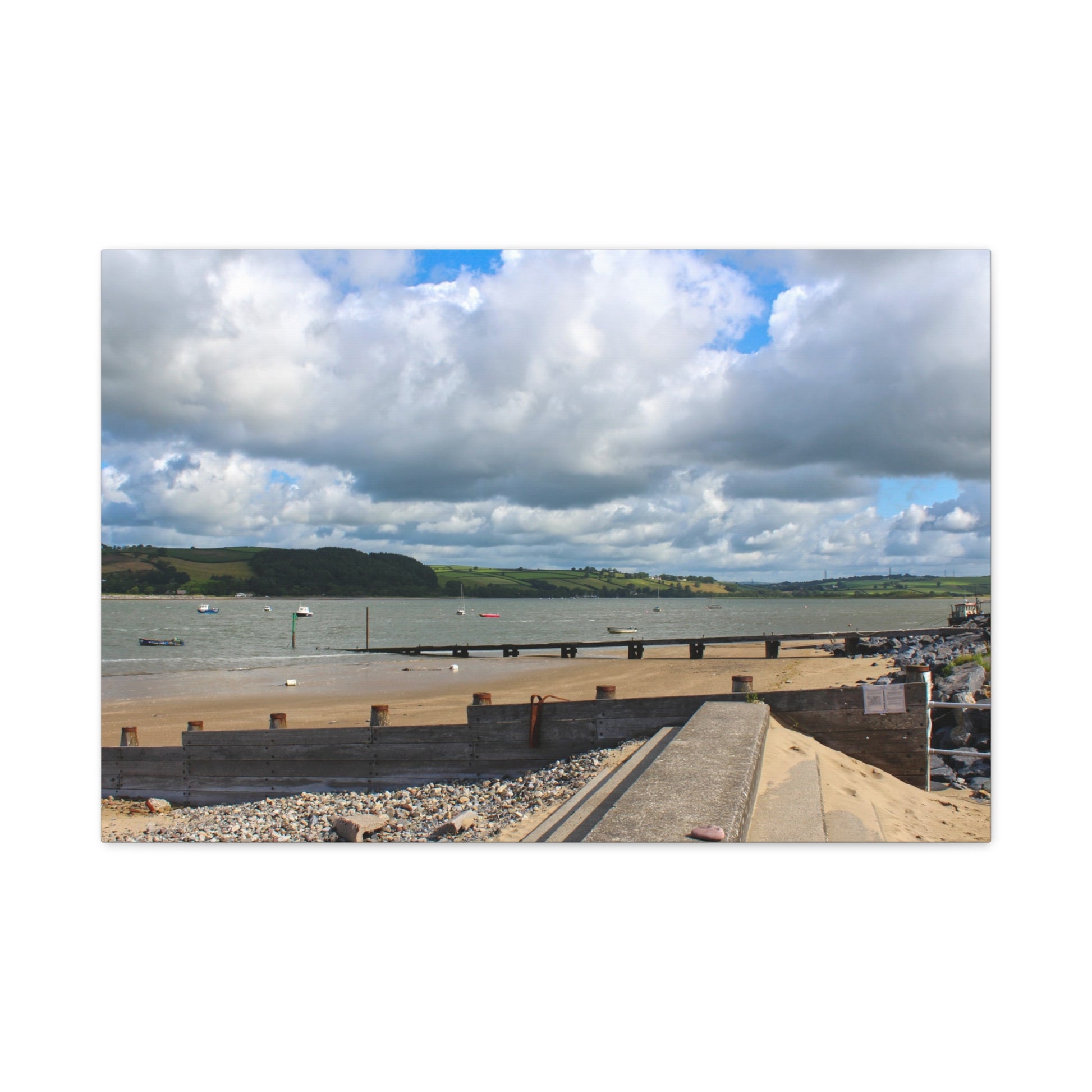 Panoramic view of a coastal scene with a road over a body of water, under a cloudy sky.