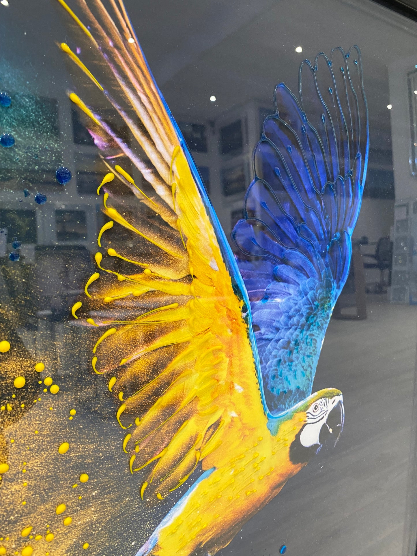 Colourful bird illustration on a reflective surface with blurred background.