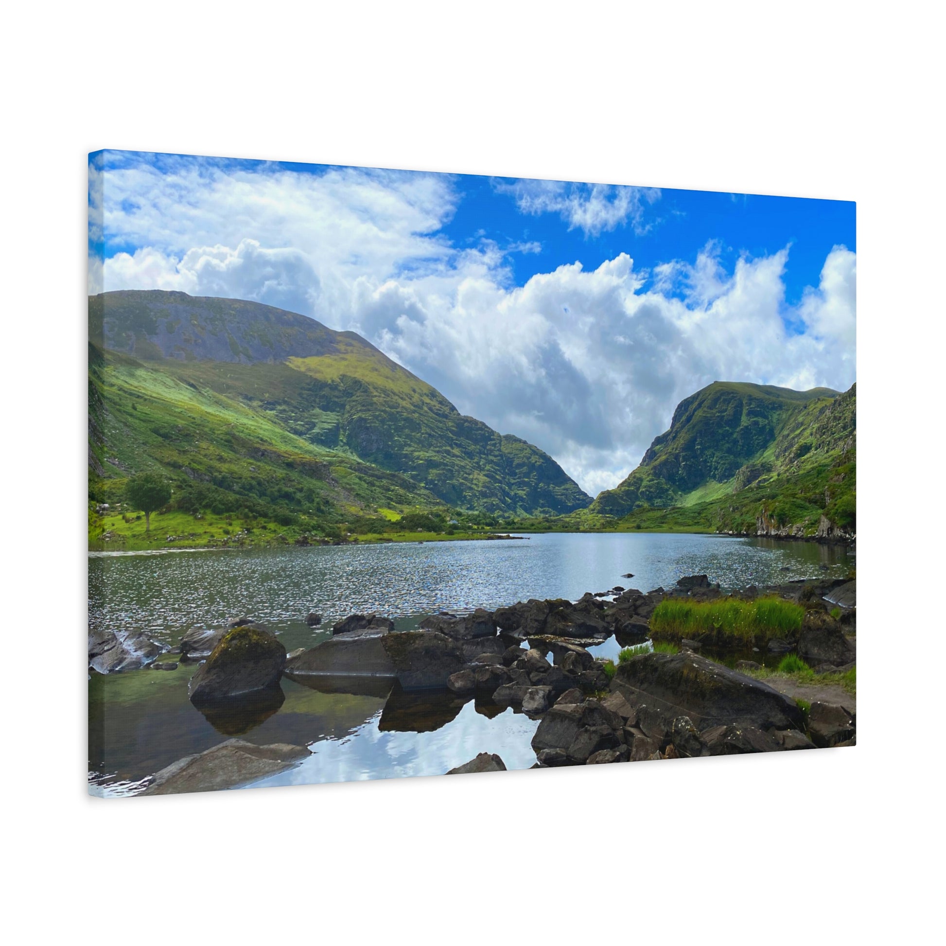 Scenic landscape with a lake and mountains under a blue sky with clouds.