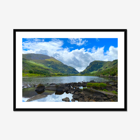 Framed photograph of a lake with mountains in the background and a blue cloudy sky.