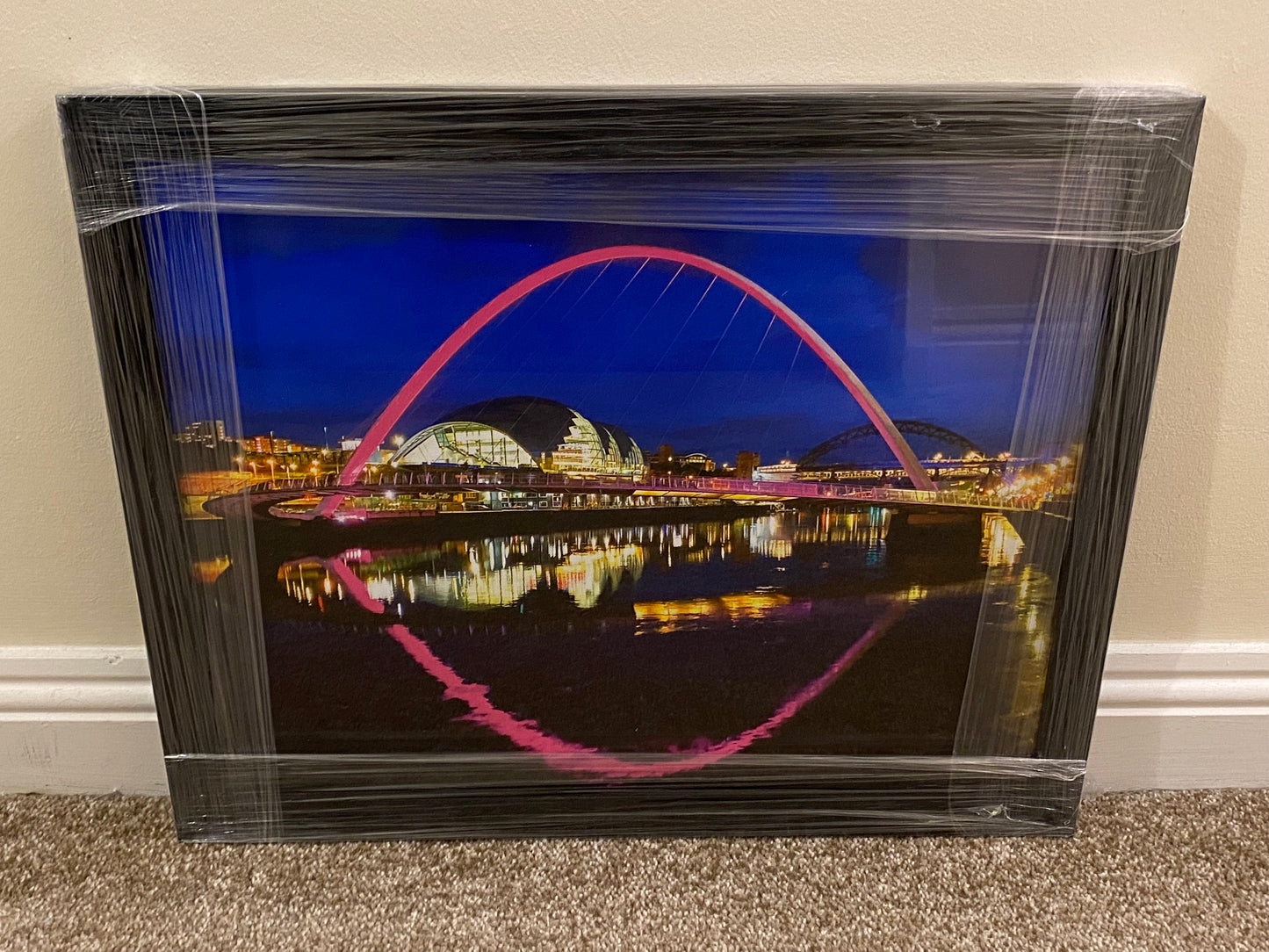 Framed photograph of a bridge at night with a cityscape in the background