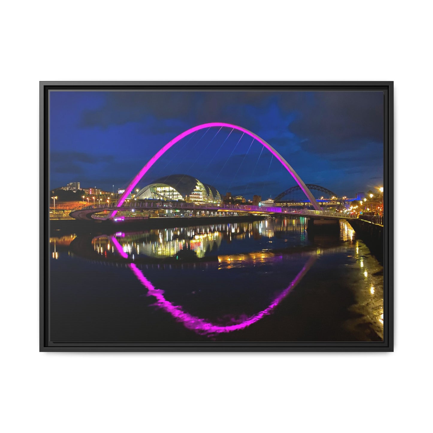 Framed photograph of a bridge with a purple arch at night, reflected in water.