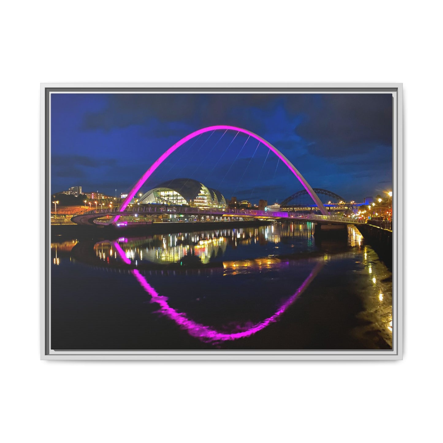 Framed photograph of a bridge with a purple arch at night, reflected in water.
