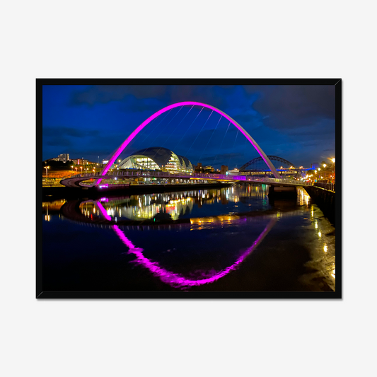 Framed photograph of a colourful arch bridge at night with a reflective water surface.
