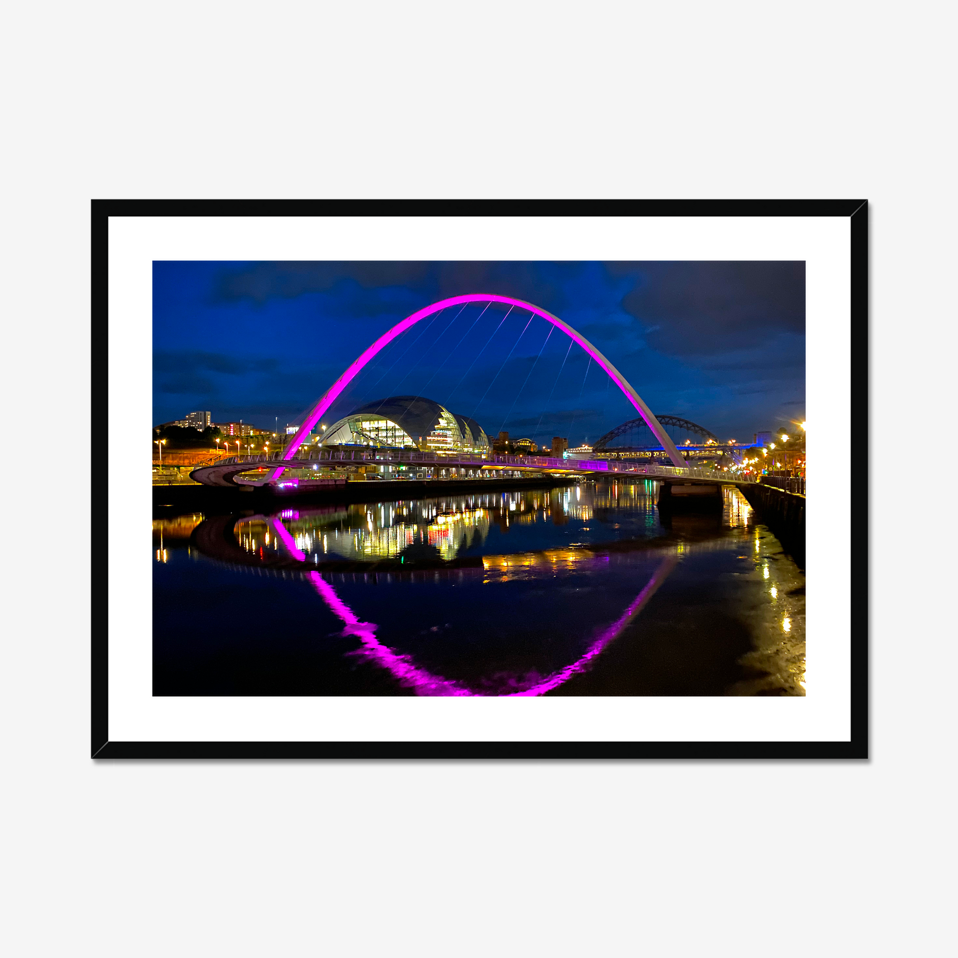 Framed photograph of a colourful arch bridge at night with a reflective water surface.