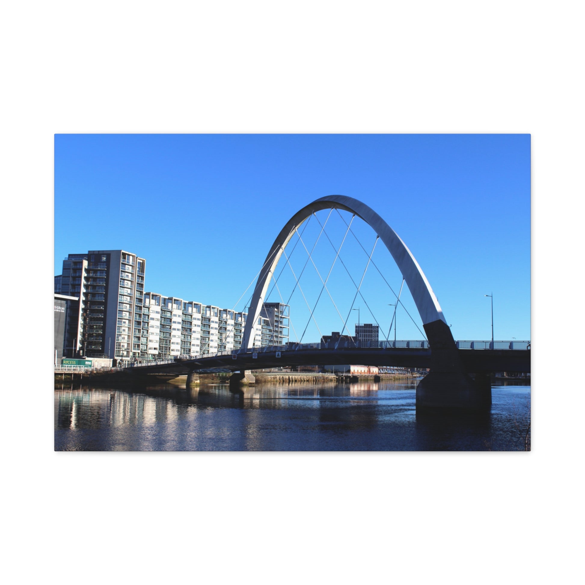 Modern arch bridge over a body of water with buildings in the background