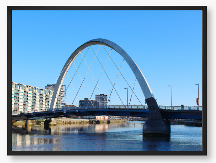A framed photo of the Glasgow Clyde Arc Bridge over the River Clyde, with a clear blue sky in the background.