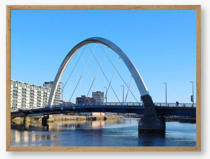 A framed photo of the Glasgow Clyde Arc Bridge over the River Clyde, with a clear blue sky in the background.