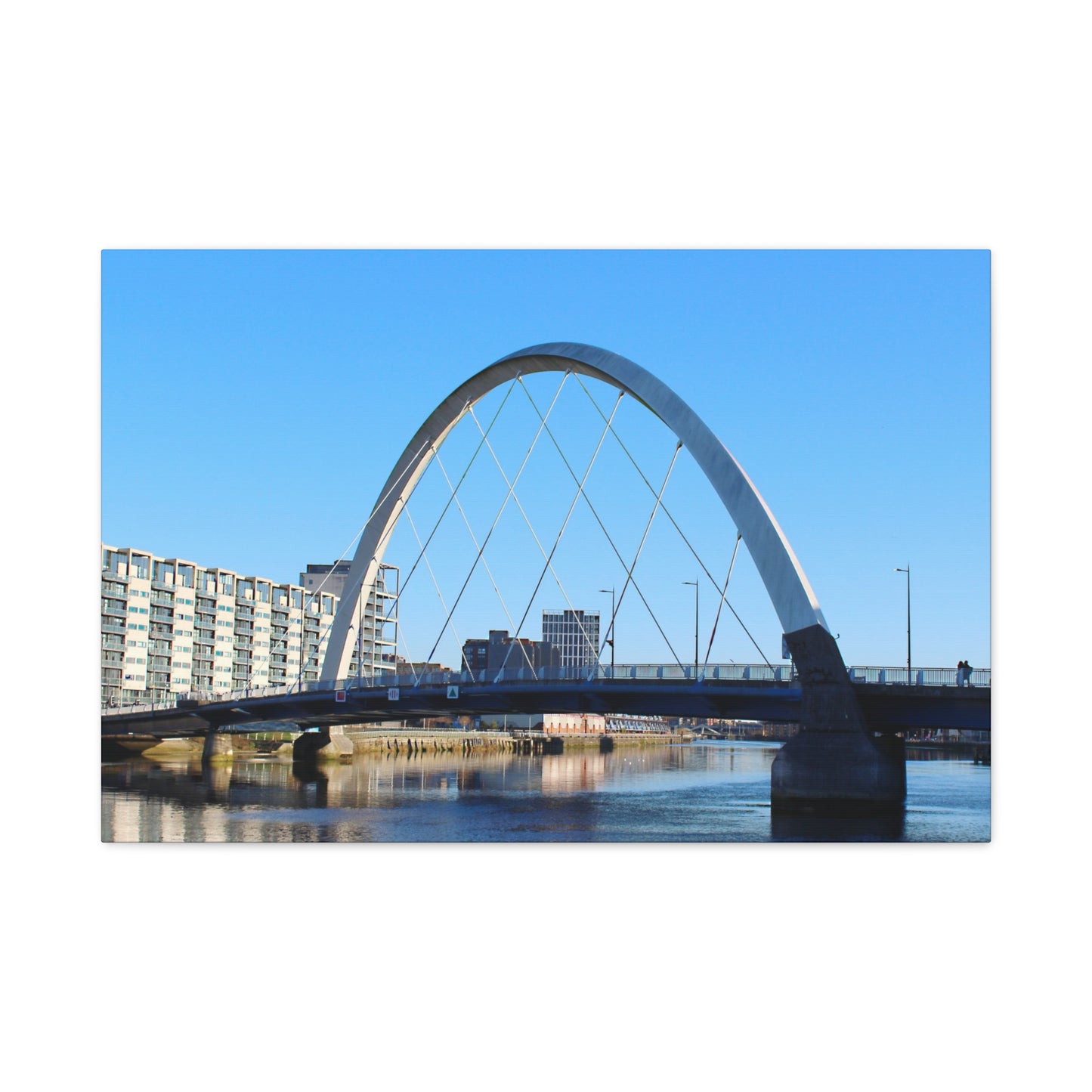 Modern arch bridge over water with buildings in the background