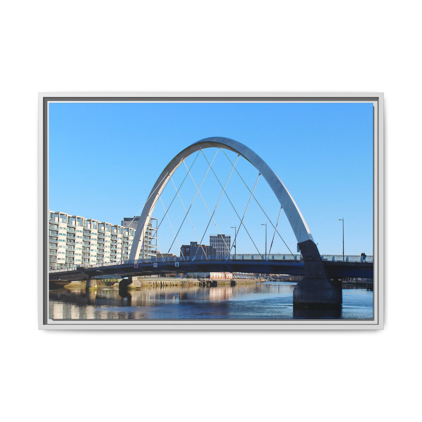 Modern arch bridge over water with buildings in the background