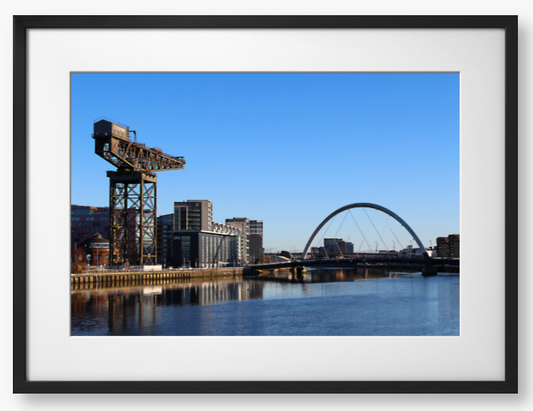 Framed Photo Of A Cityscape with a crane, buildings, and a bridge over water.