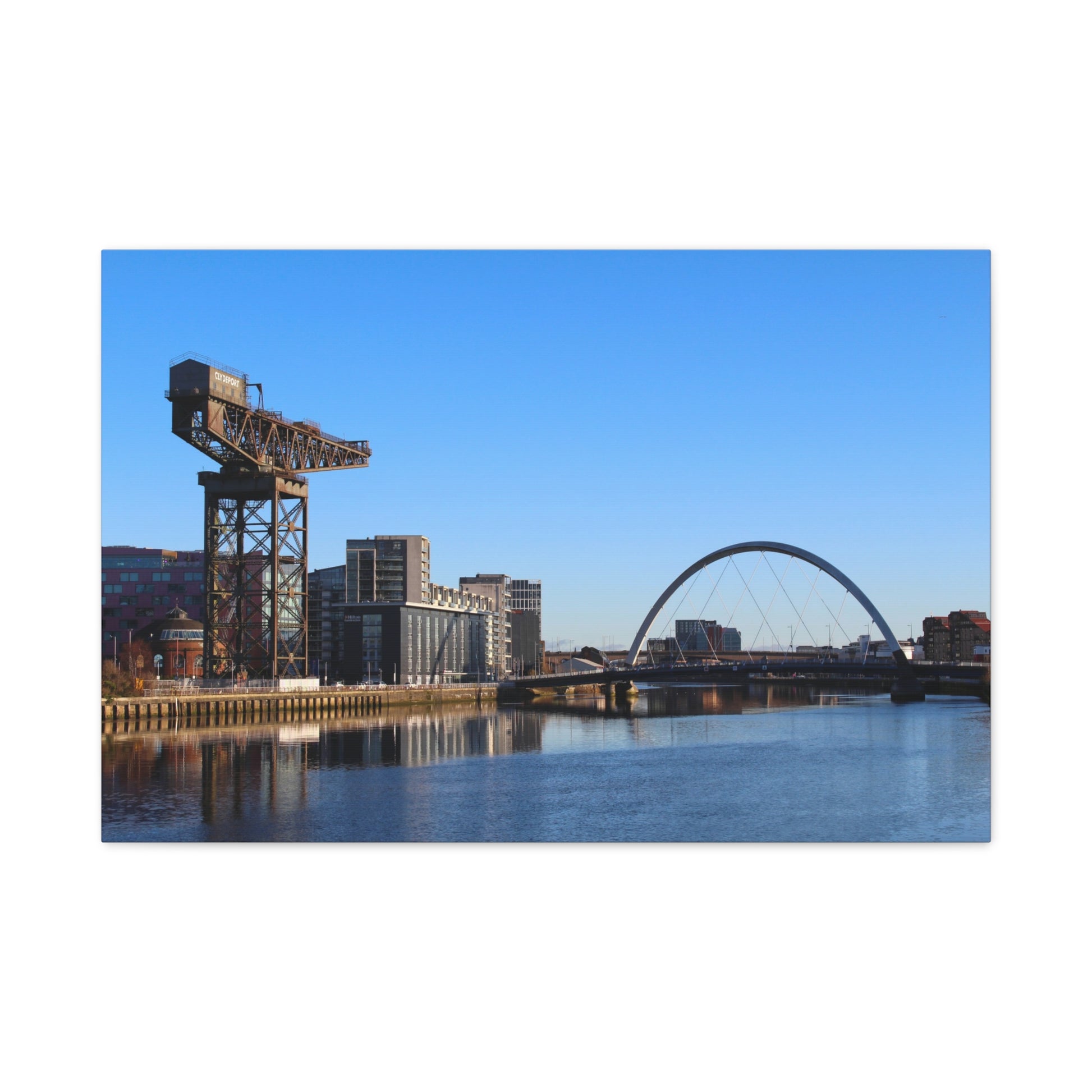 Cityscape with a crane and arch bridge over water on a clear day