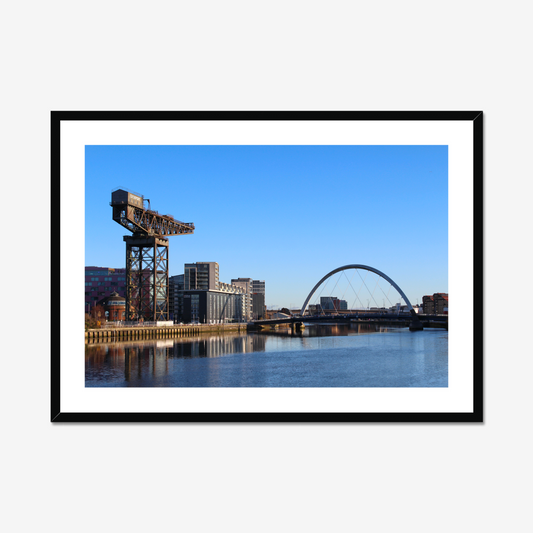 Framed photograph of a cityscape with a crane and a bridge over water.