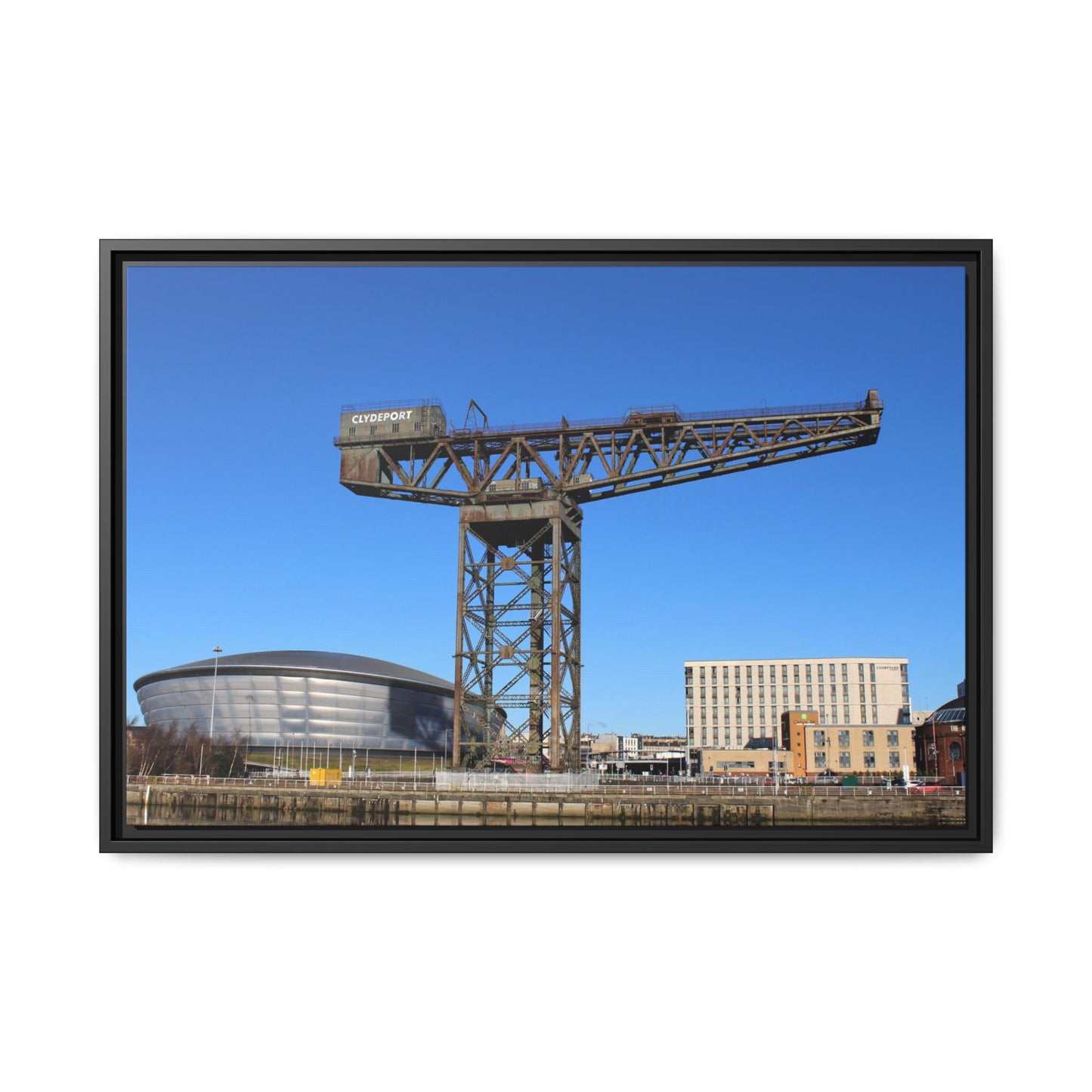 Framed photograph of a large crane with a blue sky background