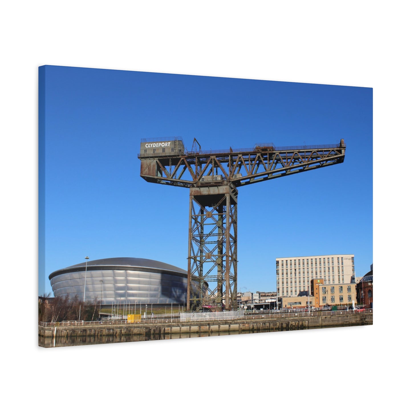 Large industrial crane with a modern building in the background under a clear blue sky.