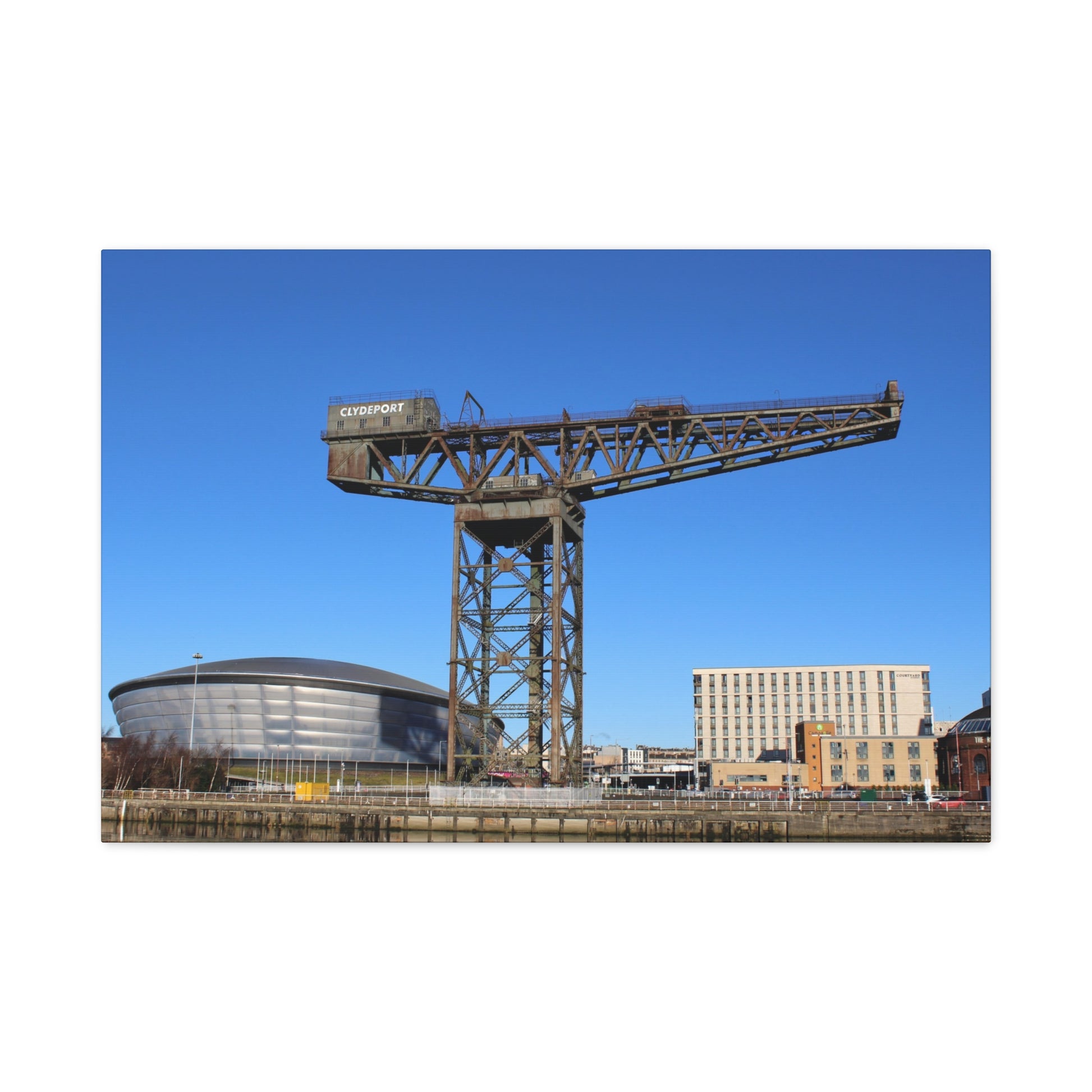 Large industrial crane with modern buildings and a blue sky in the background