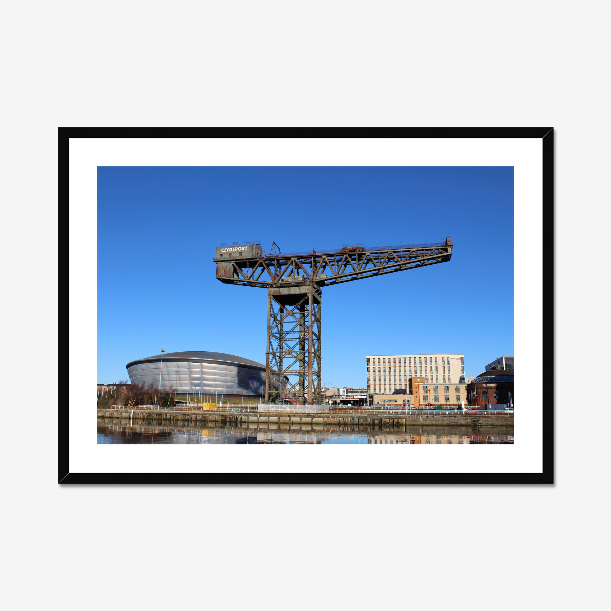 Framed photograph of a large crane with a modern building in the background