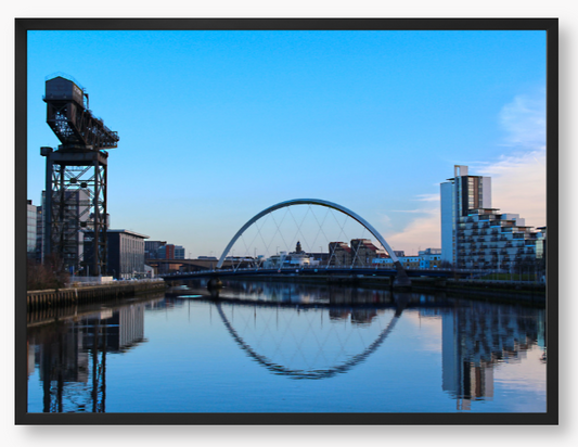 A framed print featuring a photograph of Glasgow's River Clyde with reflections, including a prominent crane and modern cityscape in the background.