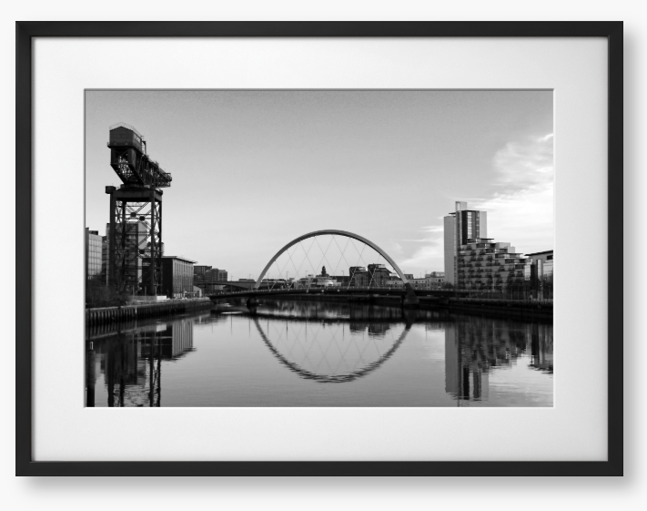 Black and White framed photograph of Glasgow's River Clyde with reflections, including a prominent crane and modern cityscape in the background.