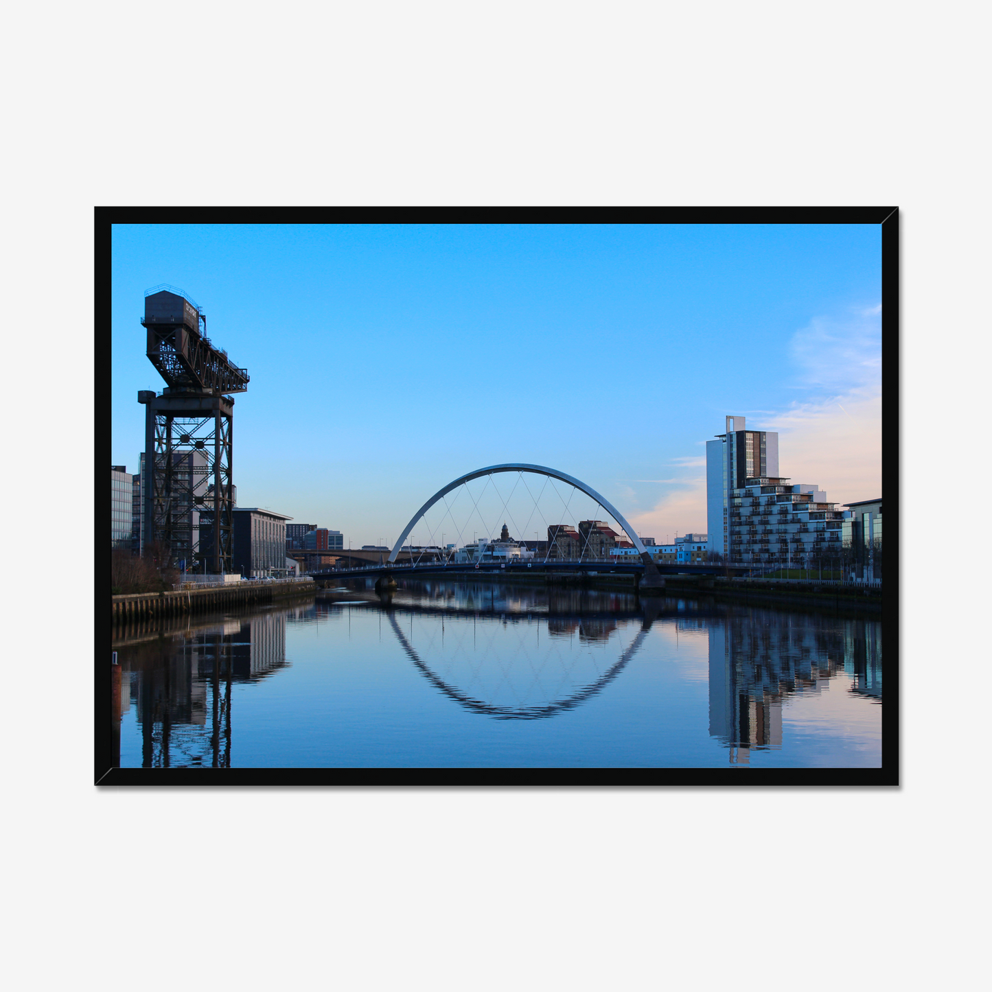 Cityscape with a crane and arch reflected in water, framed as a photograph.